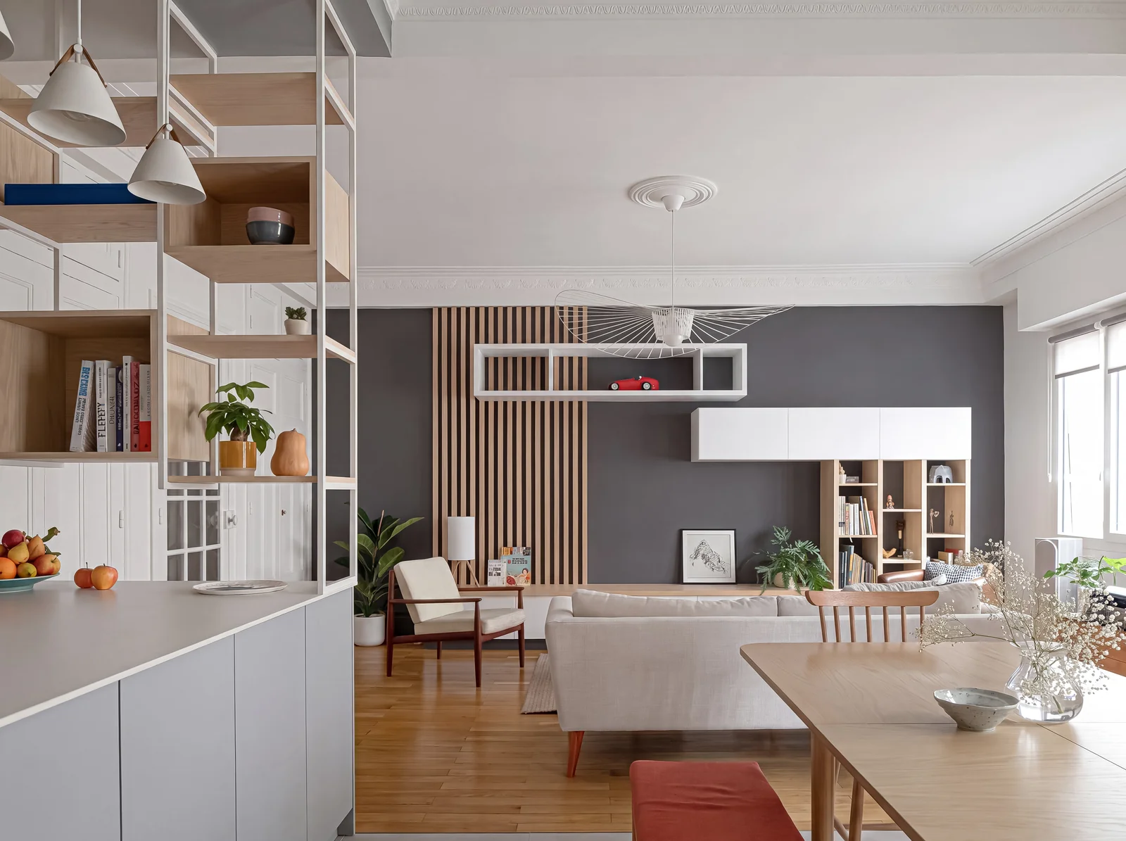 Living room with slatted oak panelling, a white floating media unit and an oak shelving divider