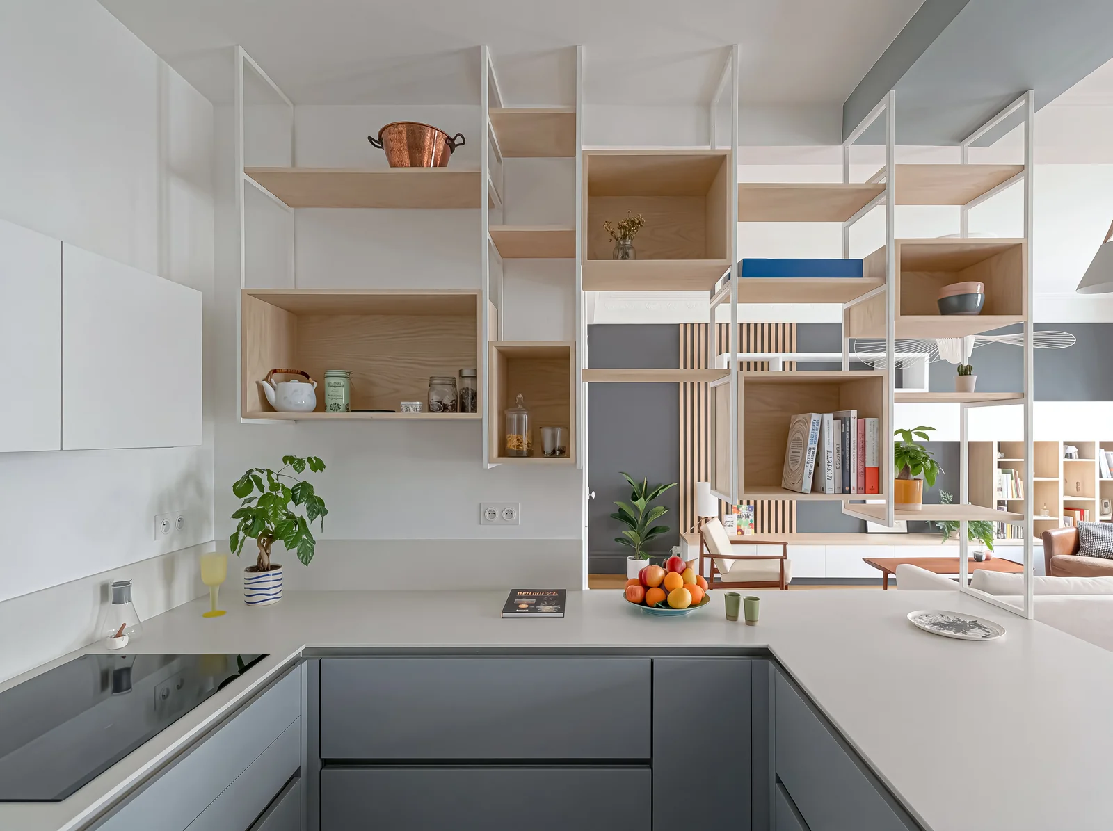 U-shaped grey kitchen with a white worktop and suspended steel shelving fitted with oak boxes