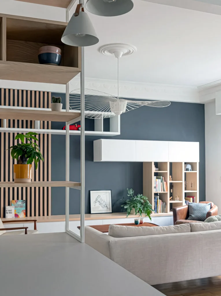 View from a kitchen worktop into a living room with oak slat panelling and white wall cabinets