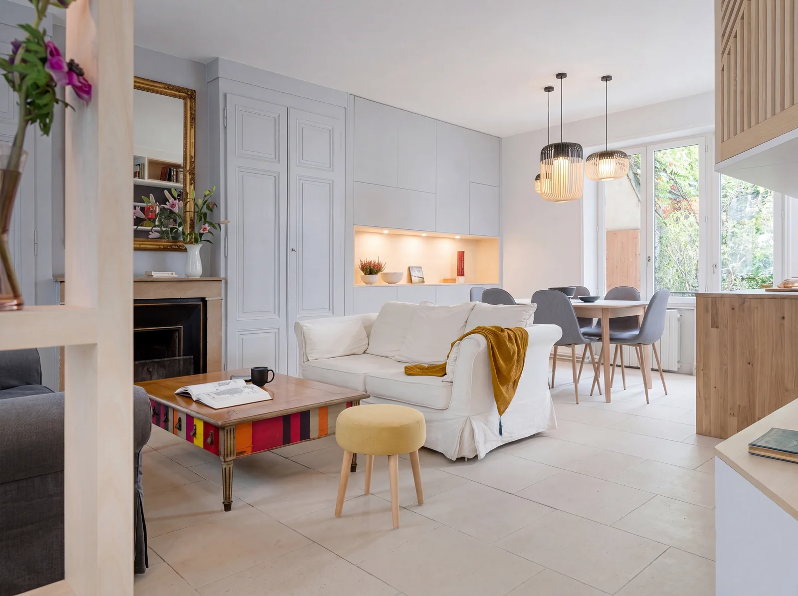 Bright living room with a white sofa, oak and white open shelving and a lit wall niche beyond