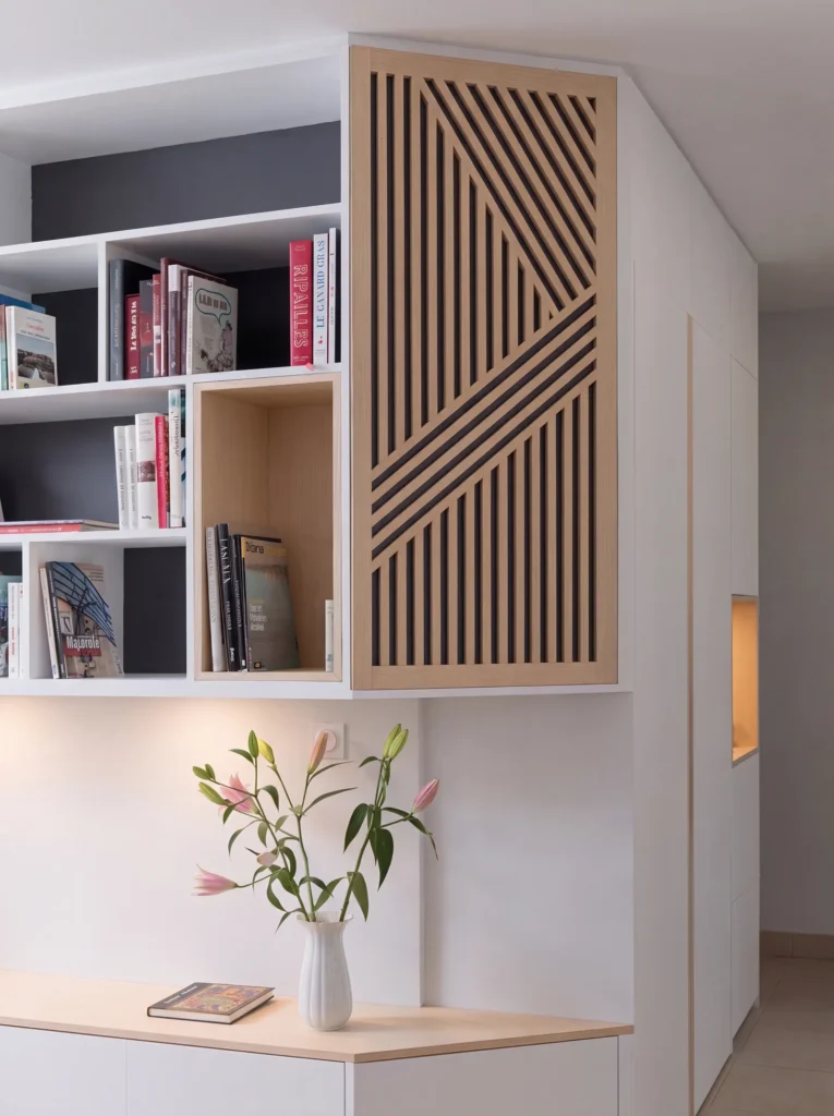 White bookcase with dark grey backs beside a diagonal oak slatted panel above a low cabinet