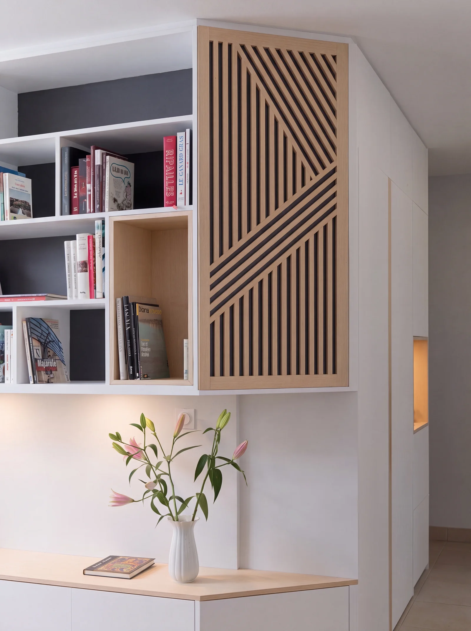 White bookcase with dark grey backs beside a diagonal oak slatted panel above a low cabinet
