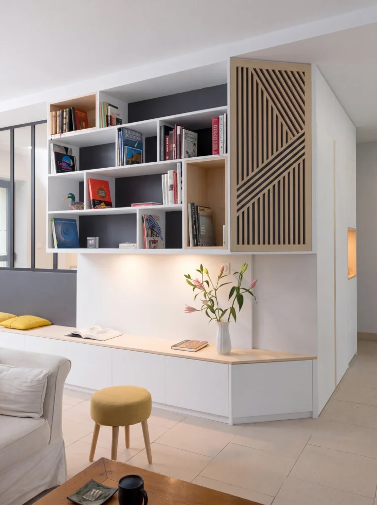 White built-in desk and bench seat beneath open bookshelves and an oak slatted cabinet door