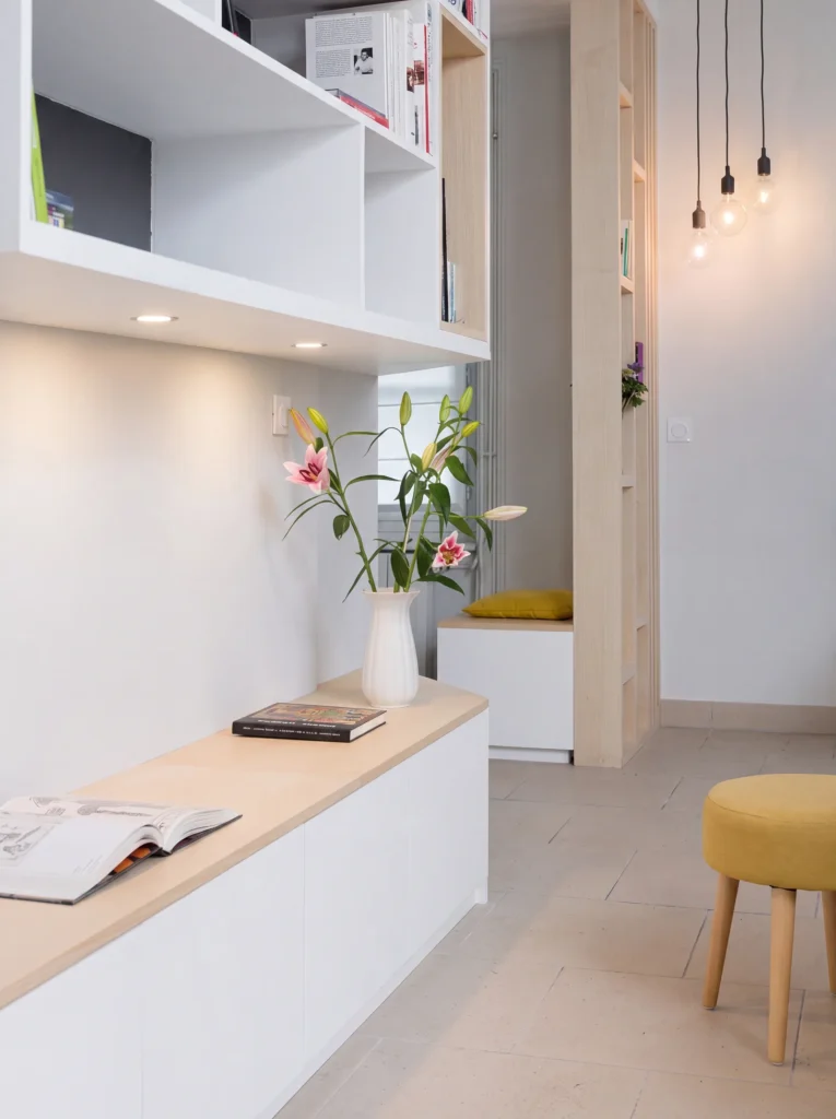 Oak-topped white window bench with lit floating shelves above and a yellow stool