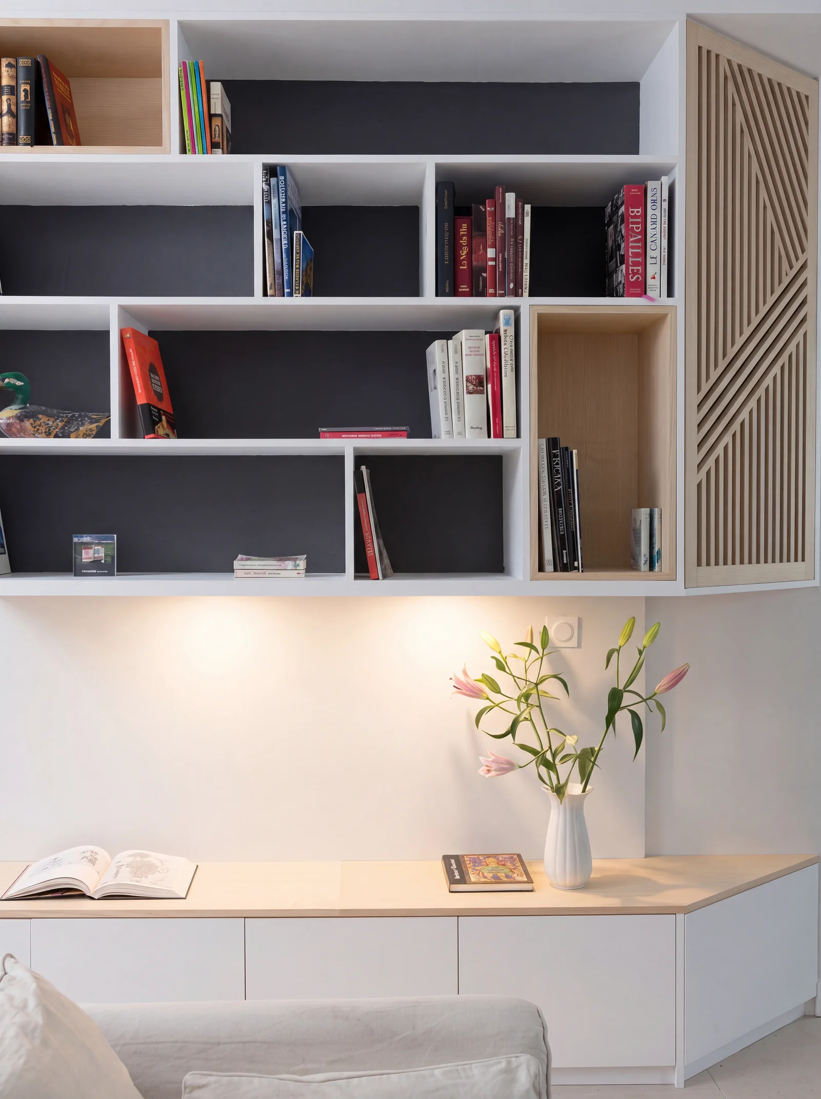 Close-up of white shelving with dark grey backs above an under-lit oak-topped sideboard