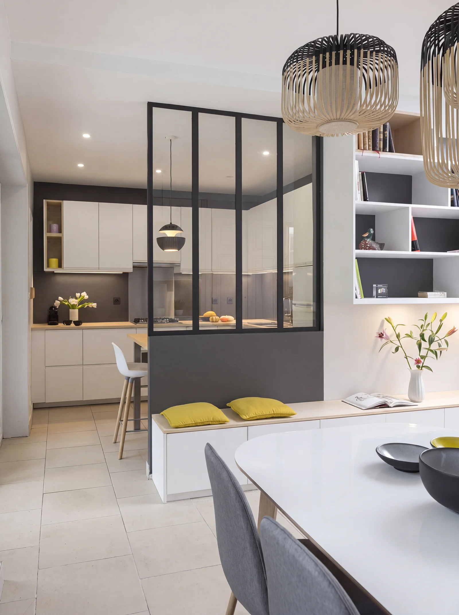 Black-framed glazed partition between a white kitchen and a dining area with a window seat