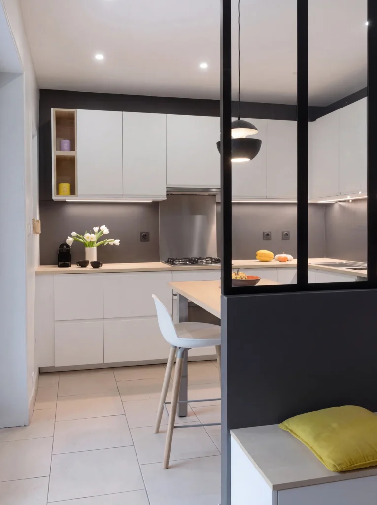 White kitchen with a breakfast bar seen through a black steel-framed glass partition