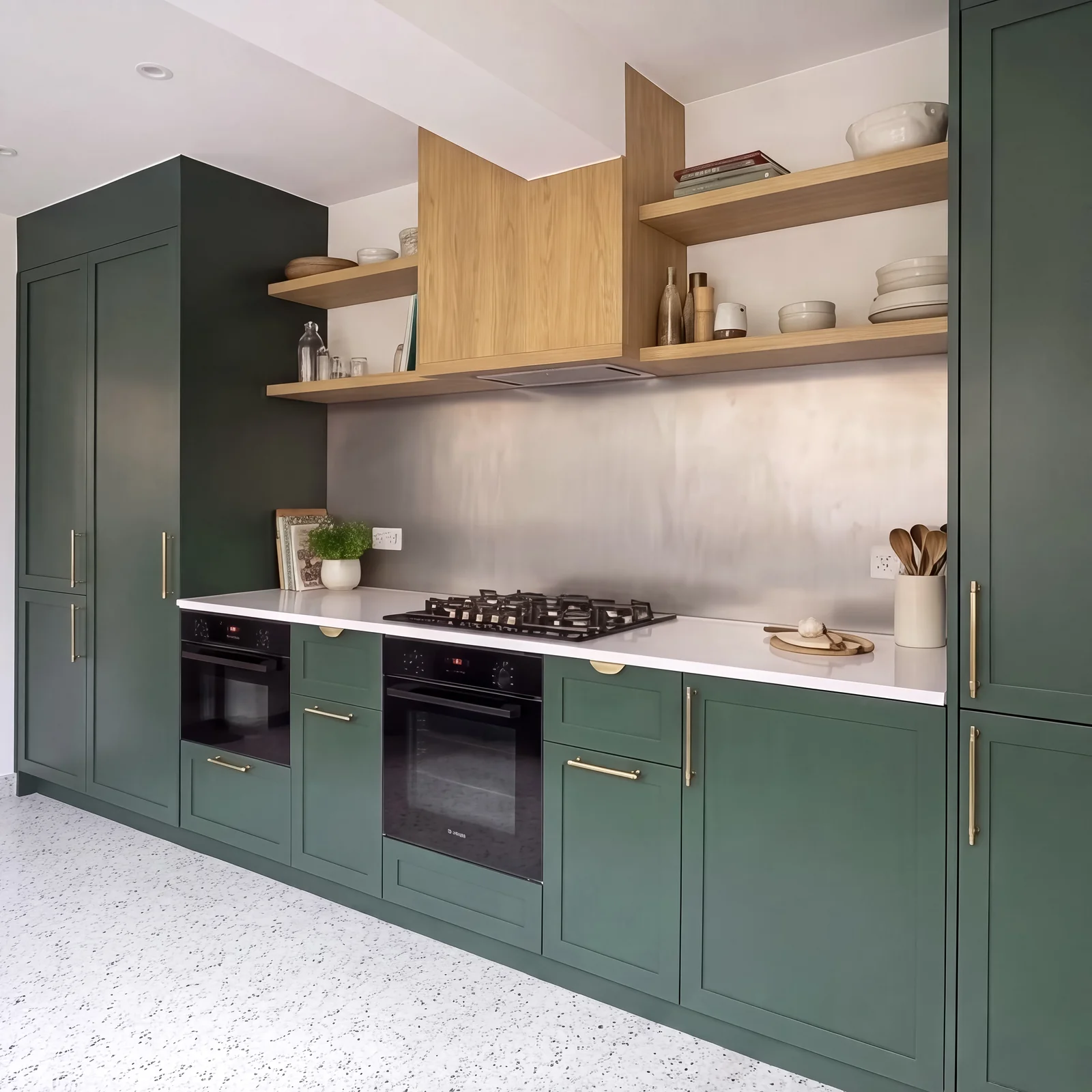 Dark green shaker kitchen with double ovens, a gas hob and oak shelving in Fulham