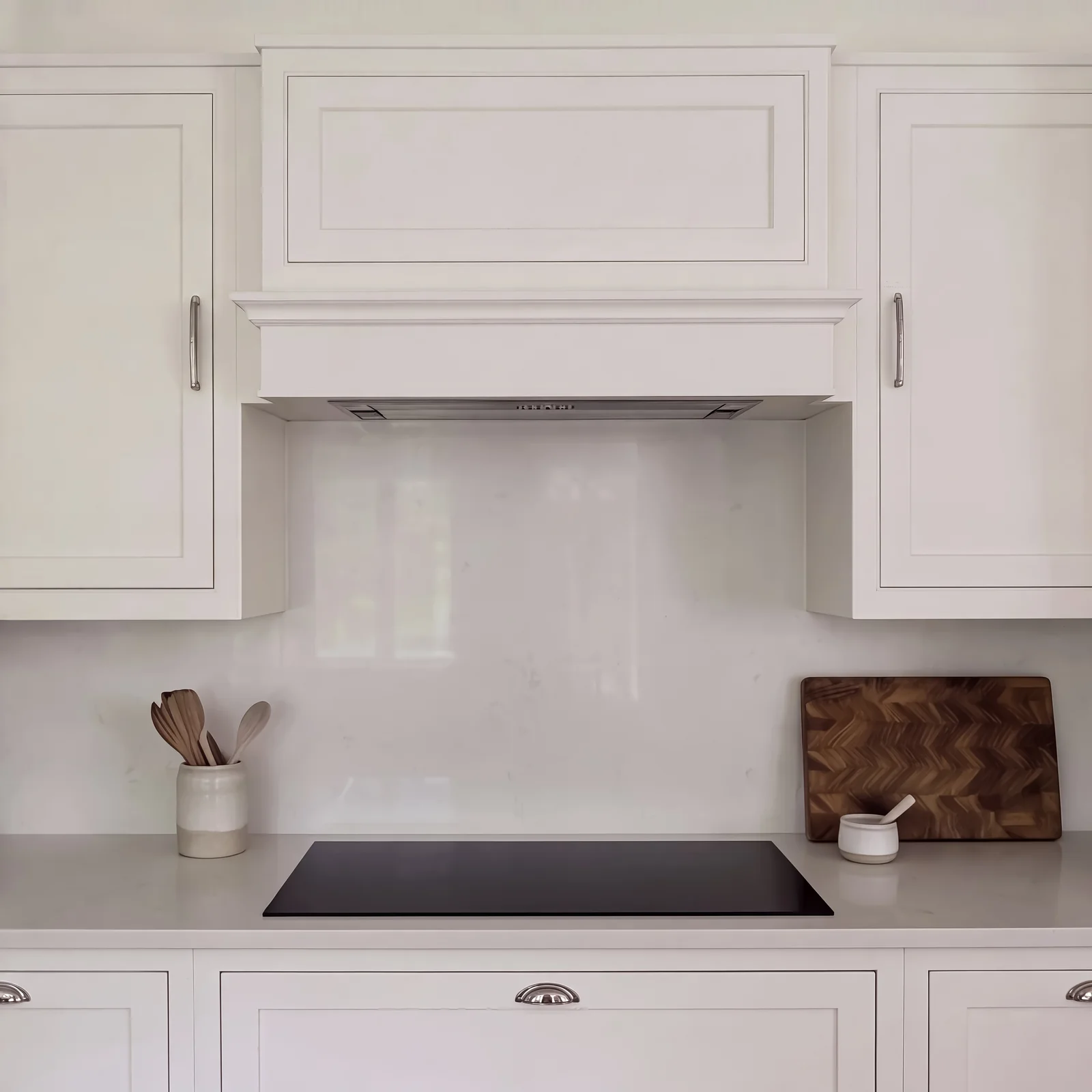 Pale grey in-frame cooker wall with a canopy hood, white splashback and induction hob