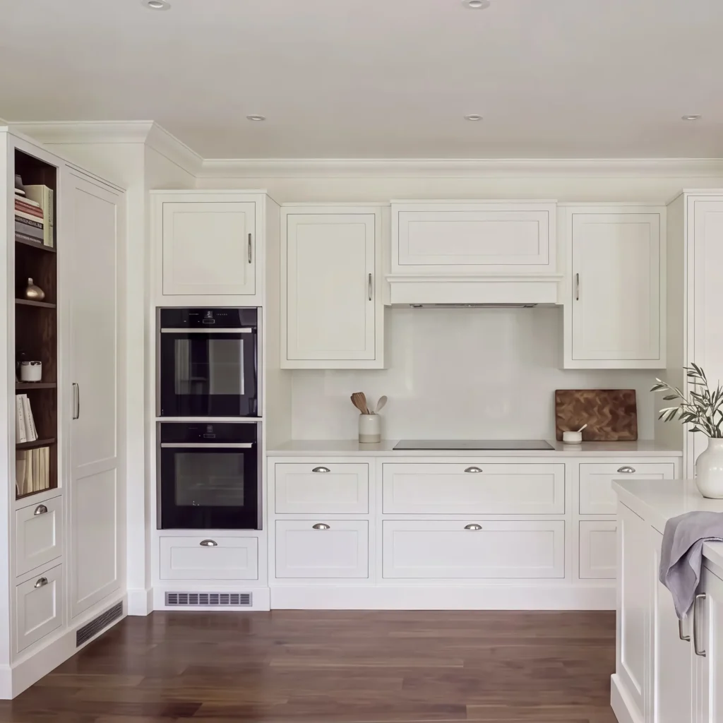 Front view of pale grey in-frame cabinets around a canopy hood, with a white island in the foreground