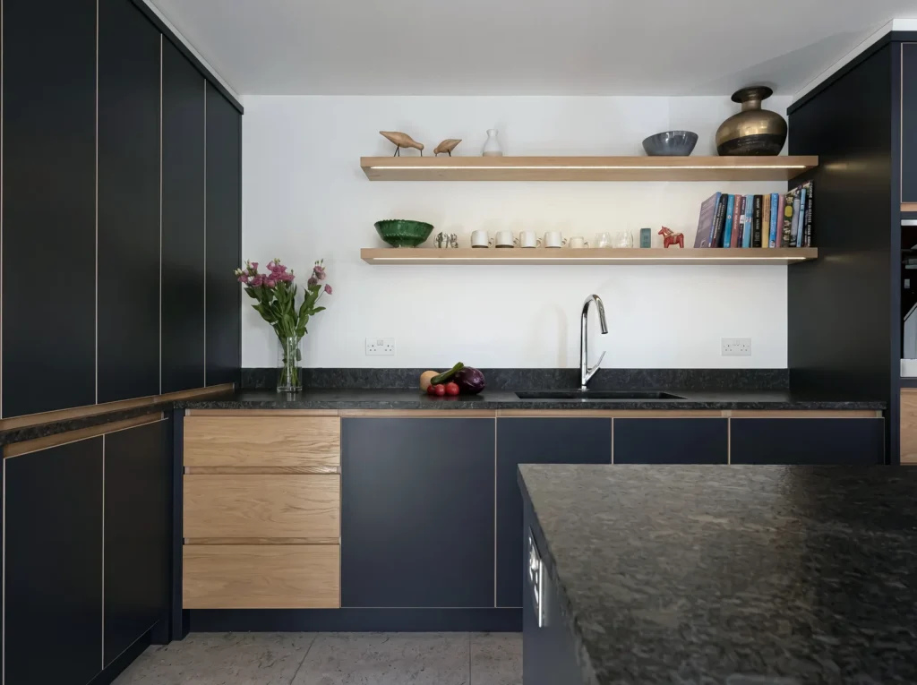 Navy handleless units with oak drawers and floating oak shelves above a granite worktop
