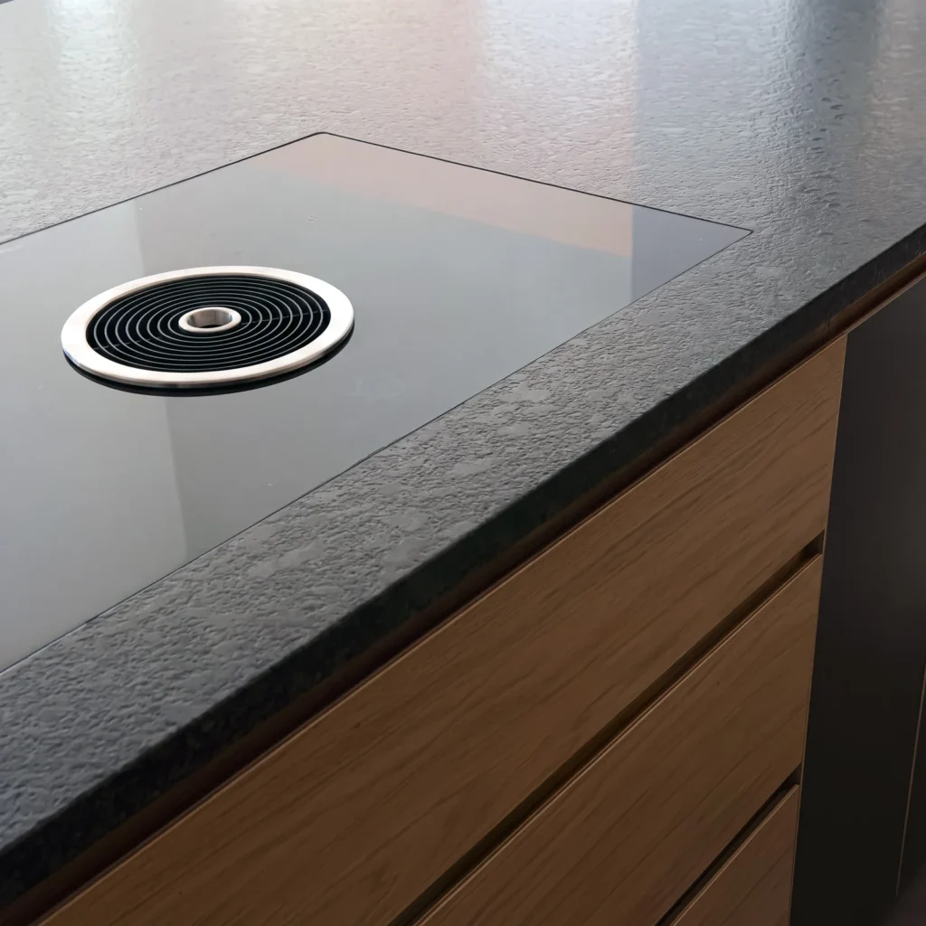 Close-up of a granite worktop with a pop-up extractor above oak drawer fronts