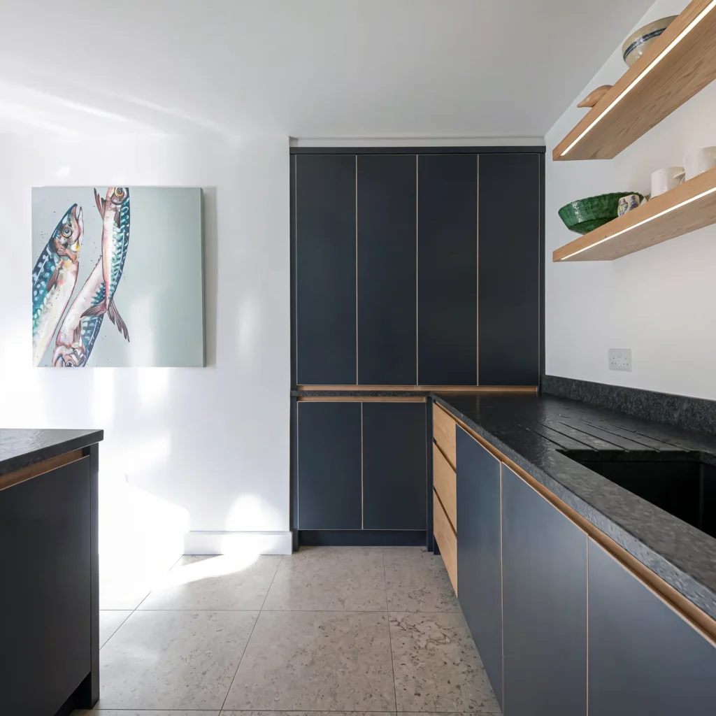 Tall navy cupboards and an L-shaped navy run with oak trim and floating shelves
