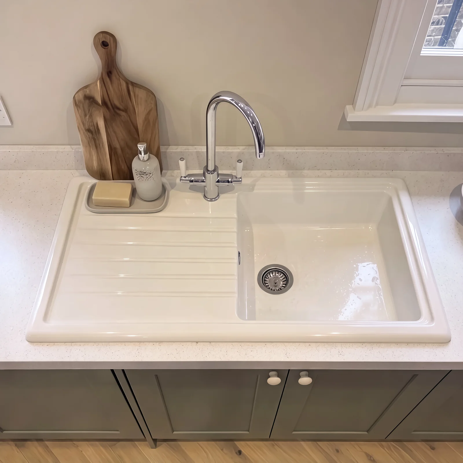 White ceramic sink with a chrome mixer tap on a sage shaker base unit