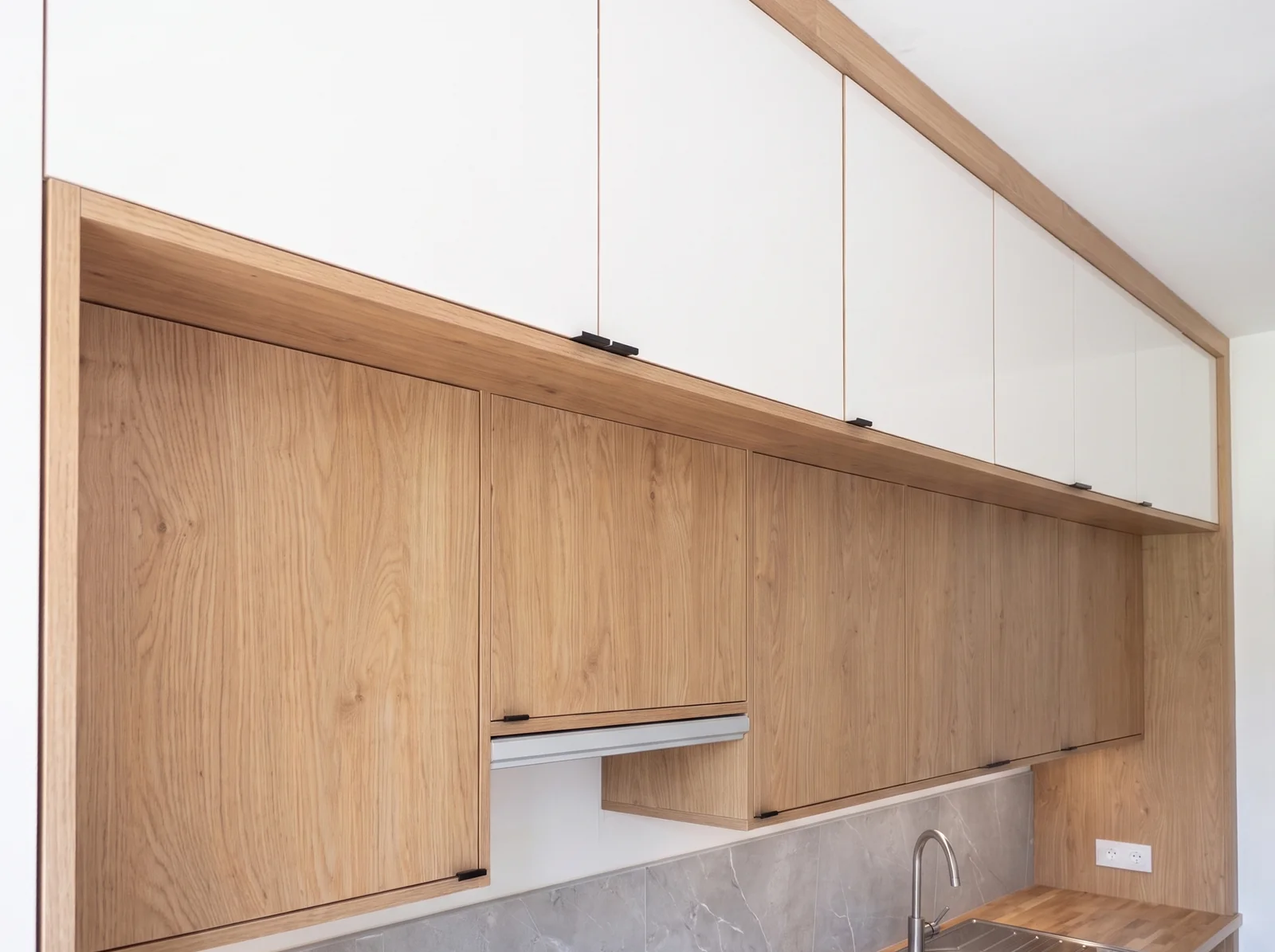 Oak wall cabinets fitted beneath white upper cupboards under a sloping ceiling