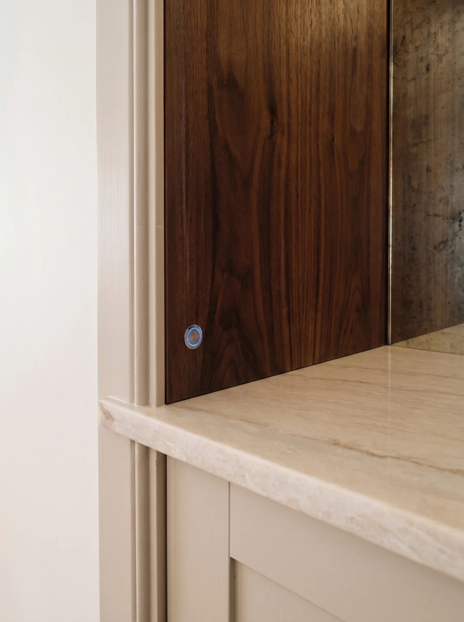 Close-up of a walnut-lined alcove edge above a cream cupboard with a marble top