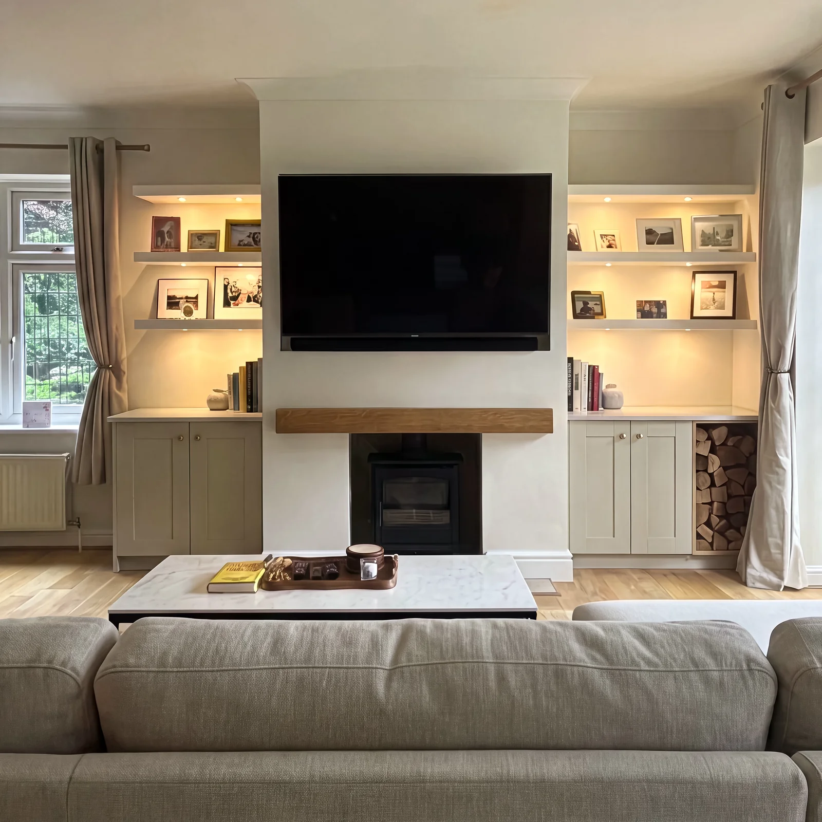 Media wall seen from the sofa, with a TV over the fireplace and lit shelves either side