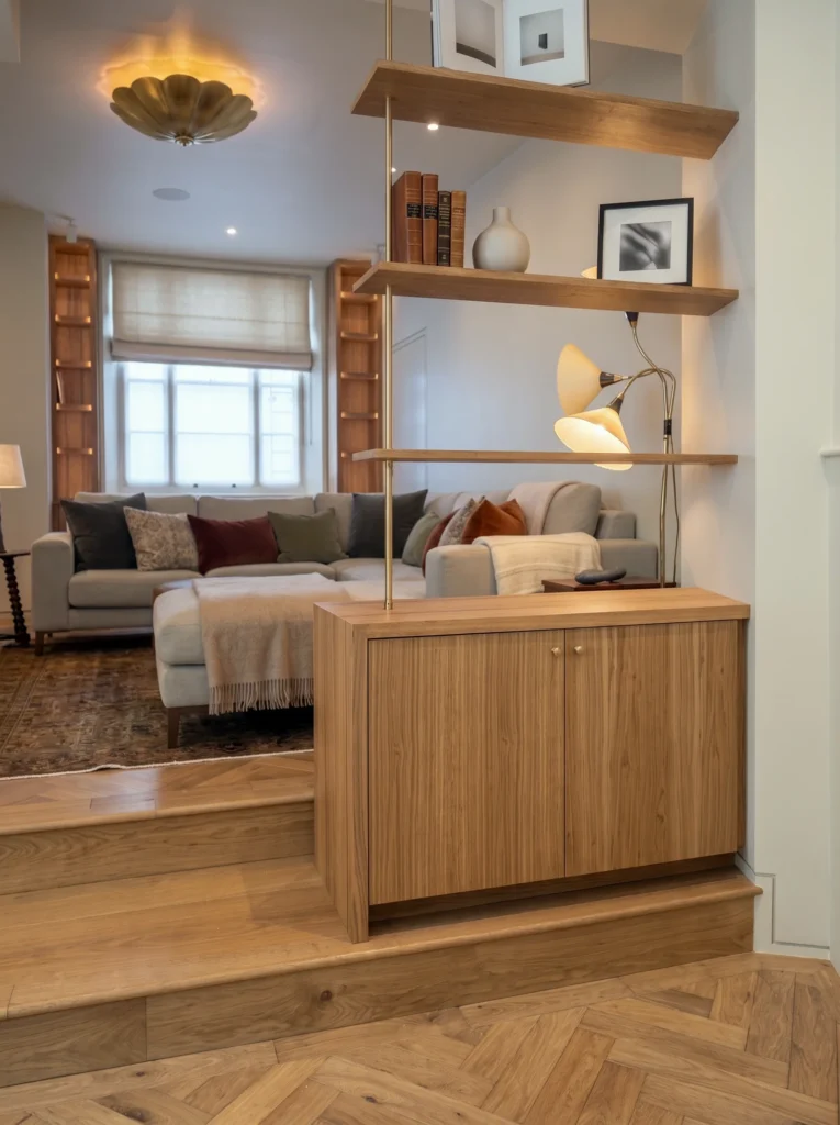 Walnut cabinet with closed doors under staggered oak shelves in a living room
