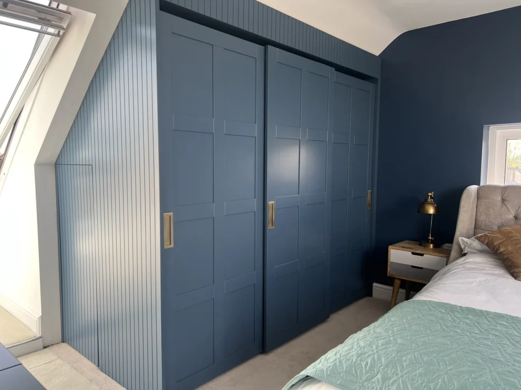 Navy shaker sliding wardrobe beside reeded navy panelling in a loft bedroom
