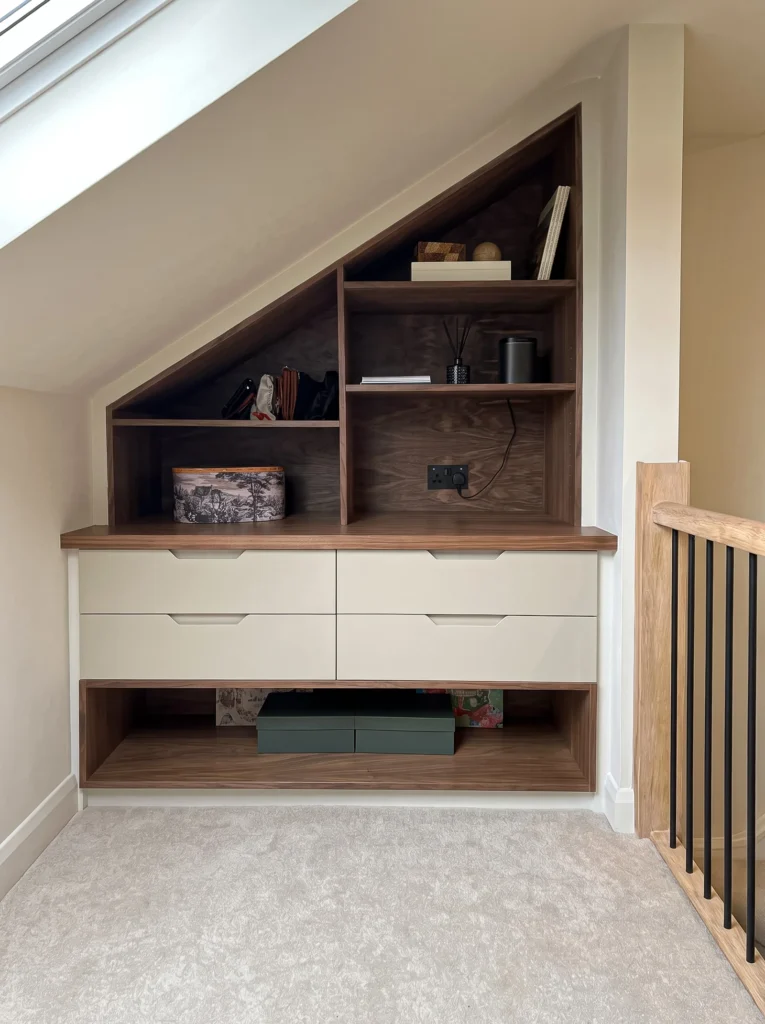 Eaves unit with dark walnut open shelving above cream drawers next to the stair rail