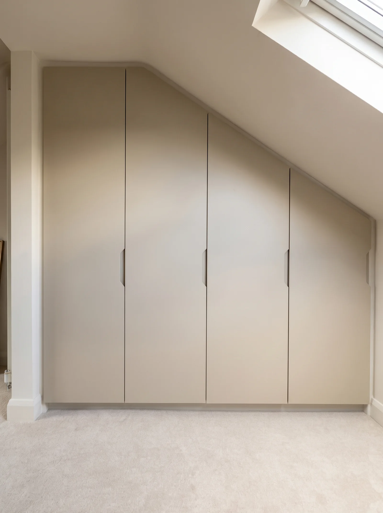 Cream handleless eaves wardrobe doors fitted under a sloping ceiling