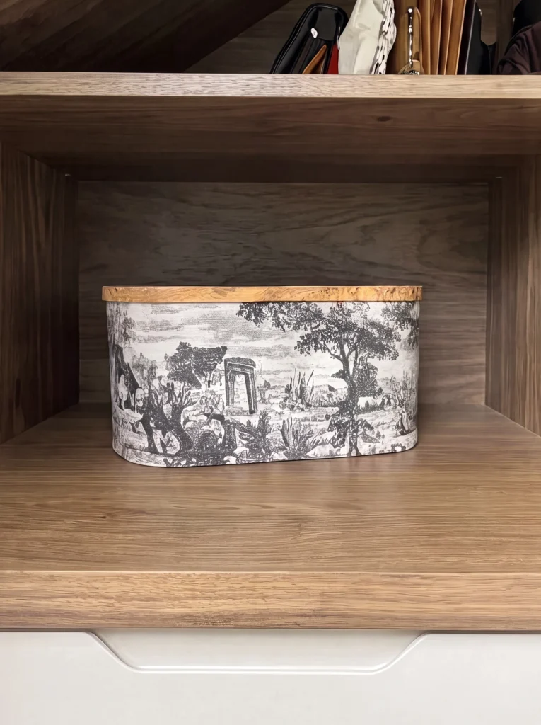 Close-up of a walnut open shelf holding a toile-printed storage box