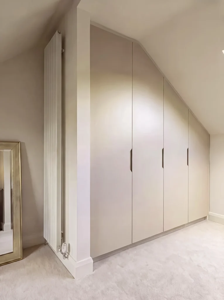 Cream eaves wardrobe with slim black handles beside a tall column radiator