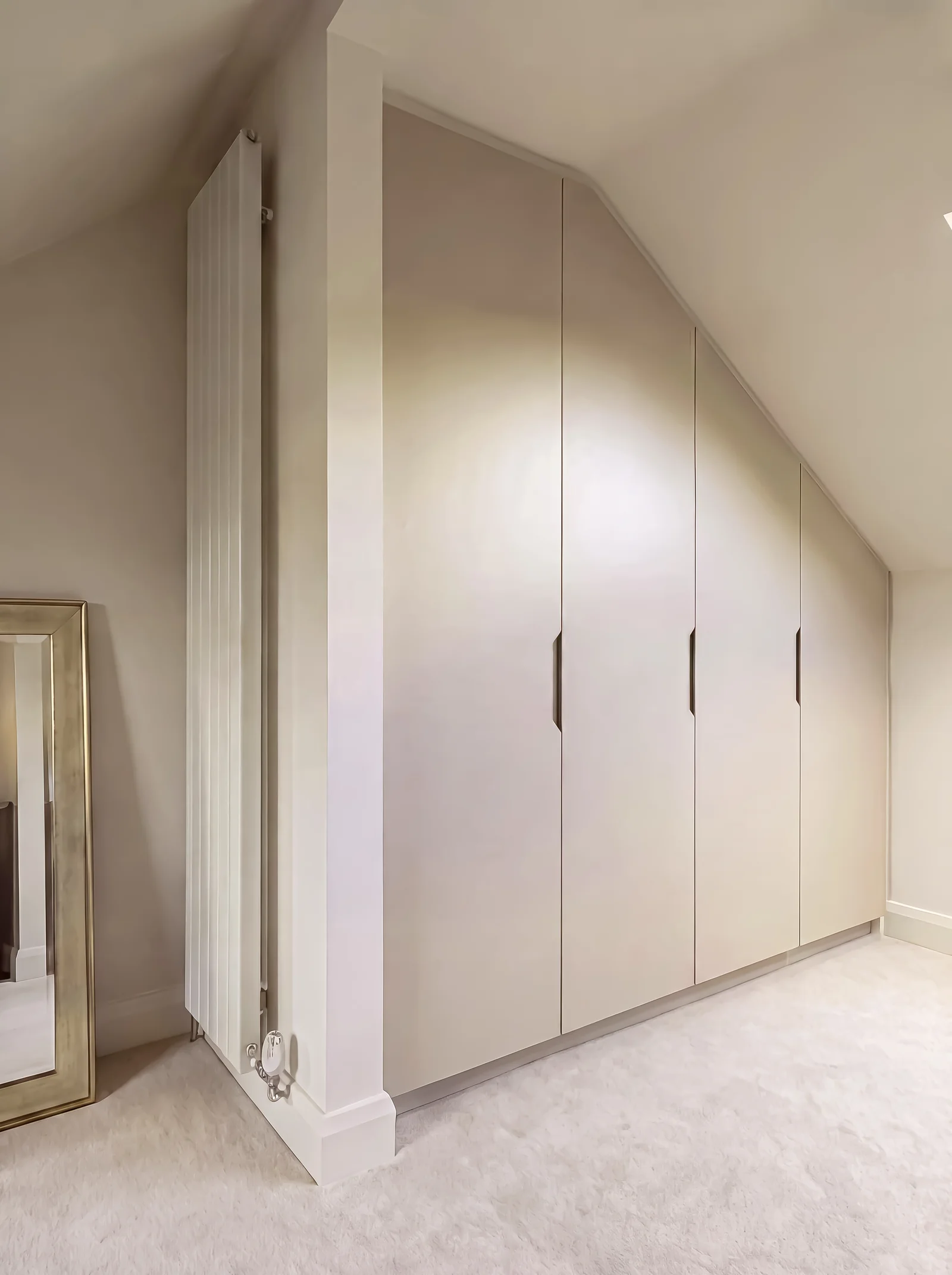 Cream eaves wardrobe with slim black handles beside a tall column radiator