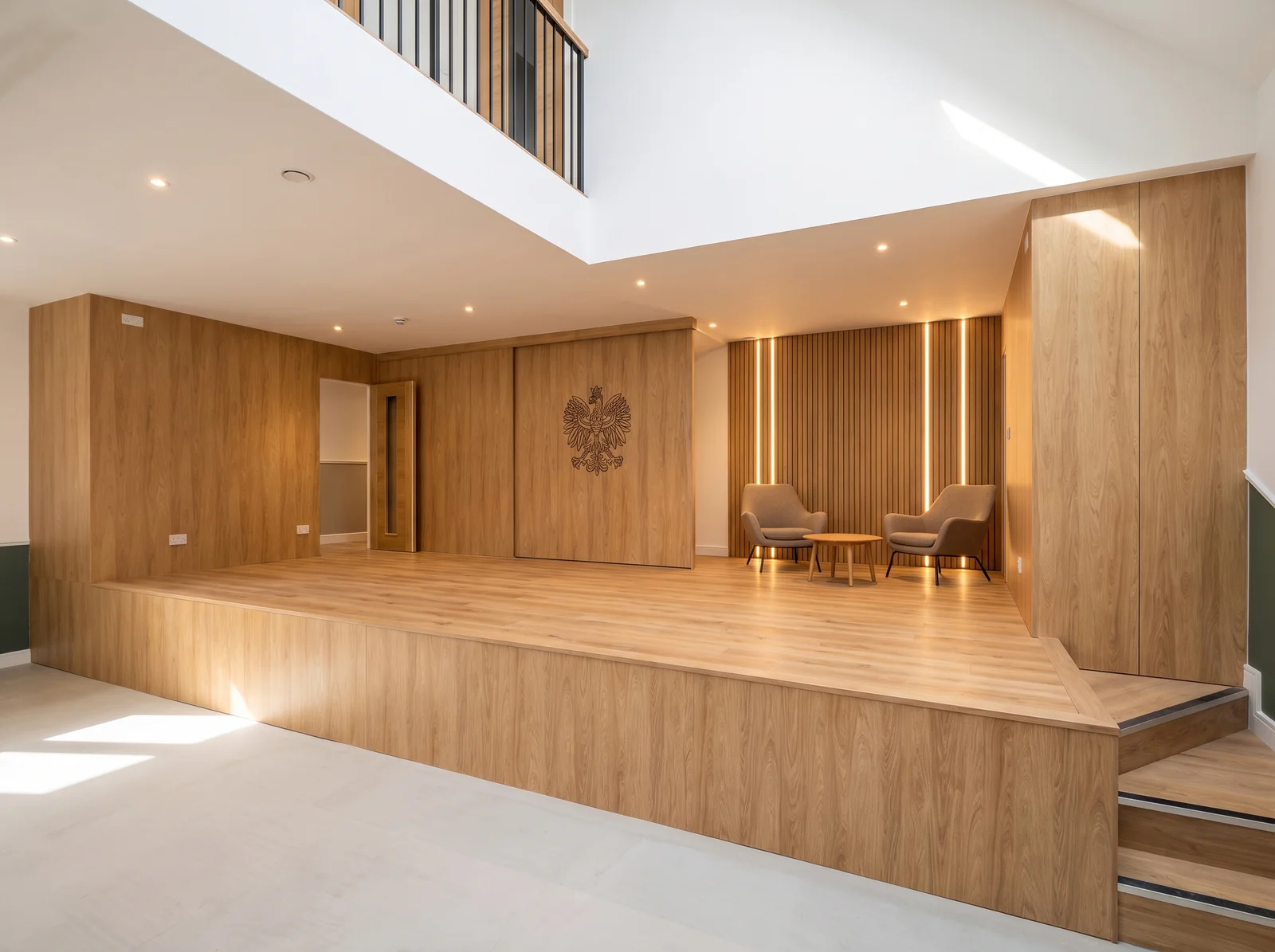 Raised oak stage with a panelled back wall, carved eagle emblem and steps in a bright hall