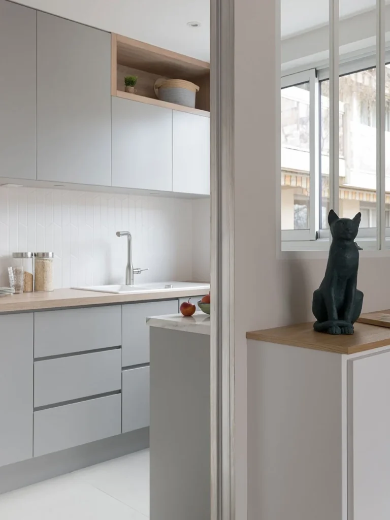 Grey handleless kitchen beside a glazed partition and an oak-topped white cabinet