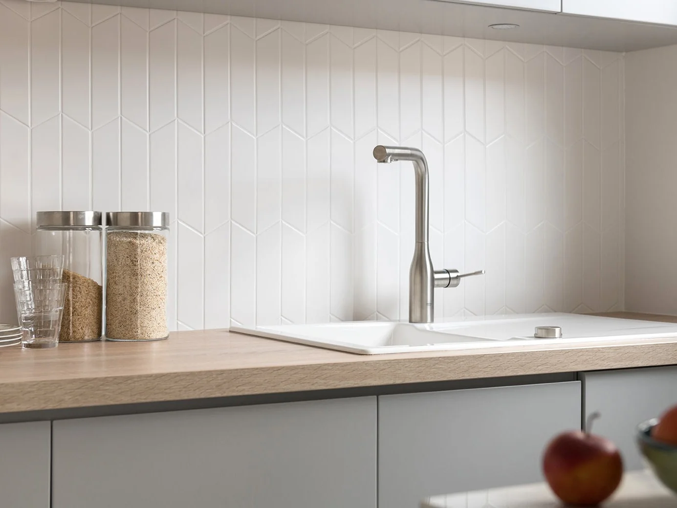 White sink and brushed steel tap on an oak worktop over grey handleless units