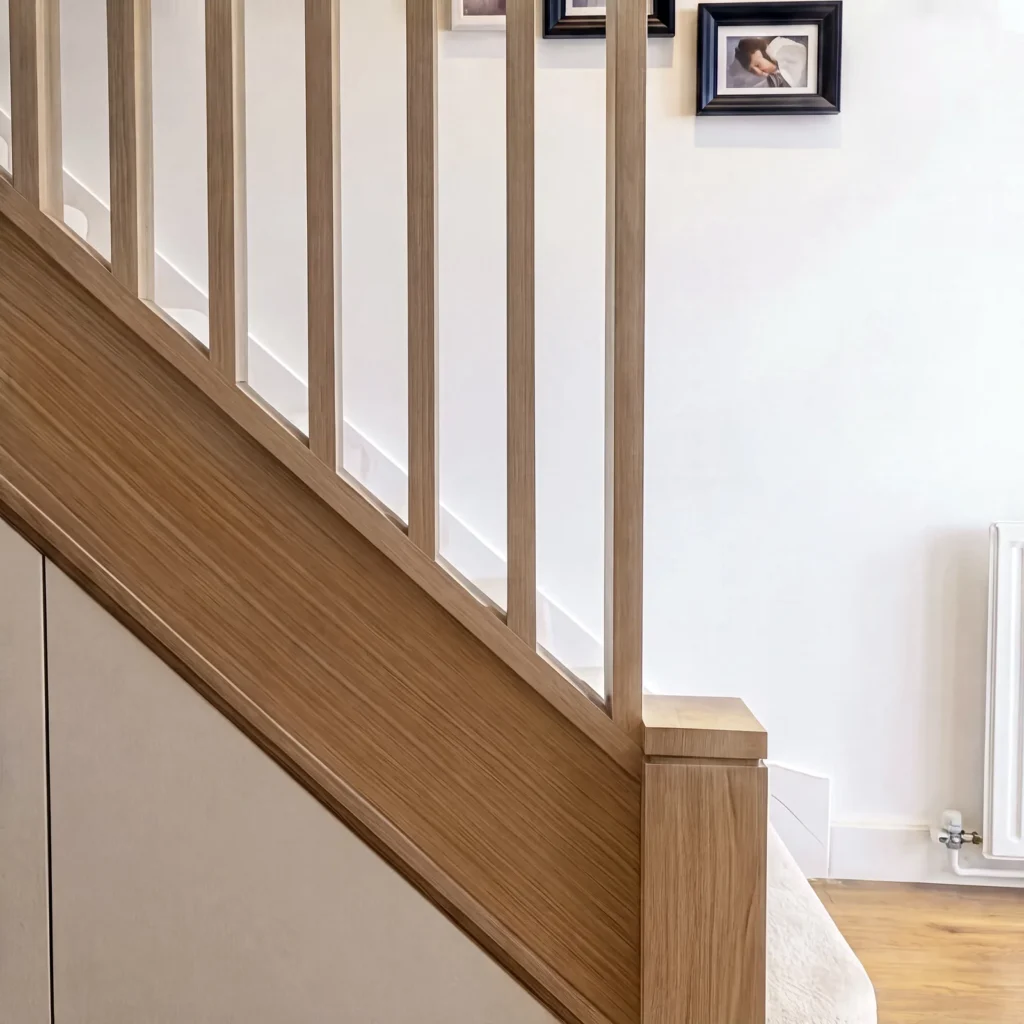 Oak newel post and spindles above white understairs storage doors