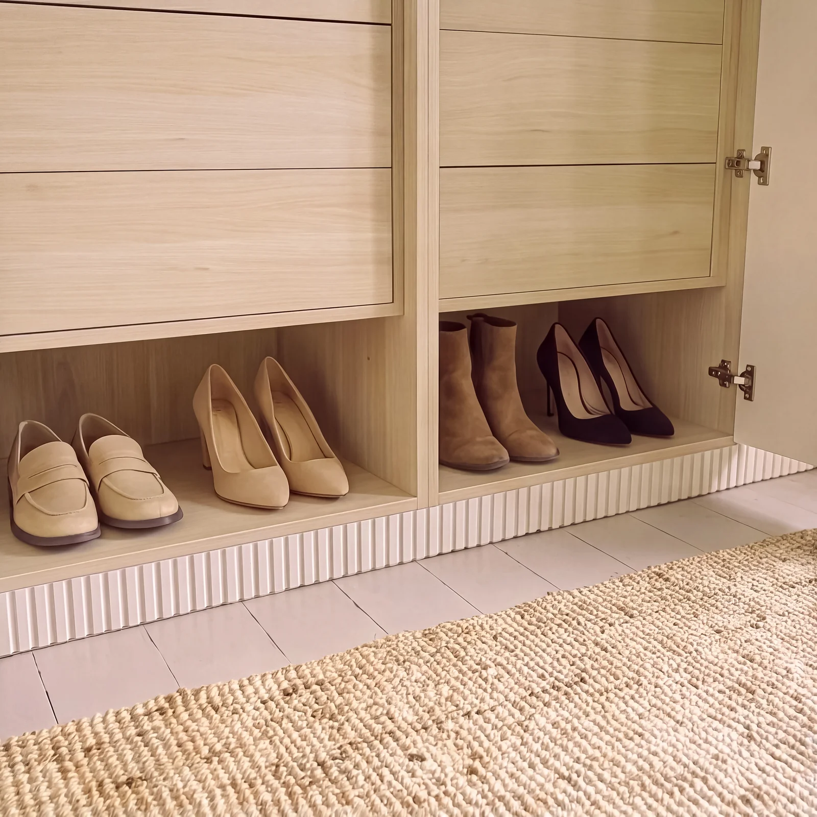Light oak shoe shelf and drawers inside a blush wardrobe above a jute rug