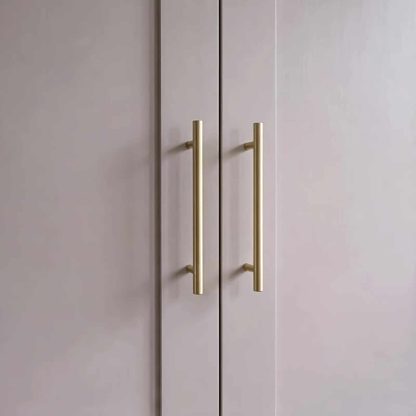 Close-up of long brass bar handles on pale grey shaker wardrobe doors