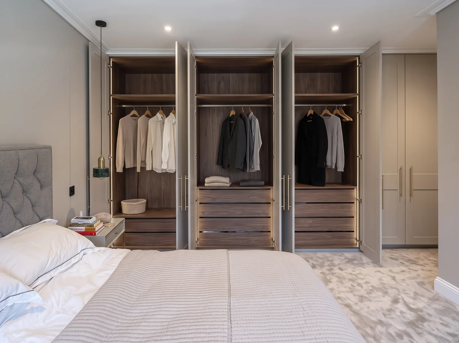 Open grey wardrobes showing walnut interiors with hanging rails and drawers