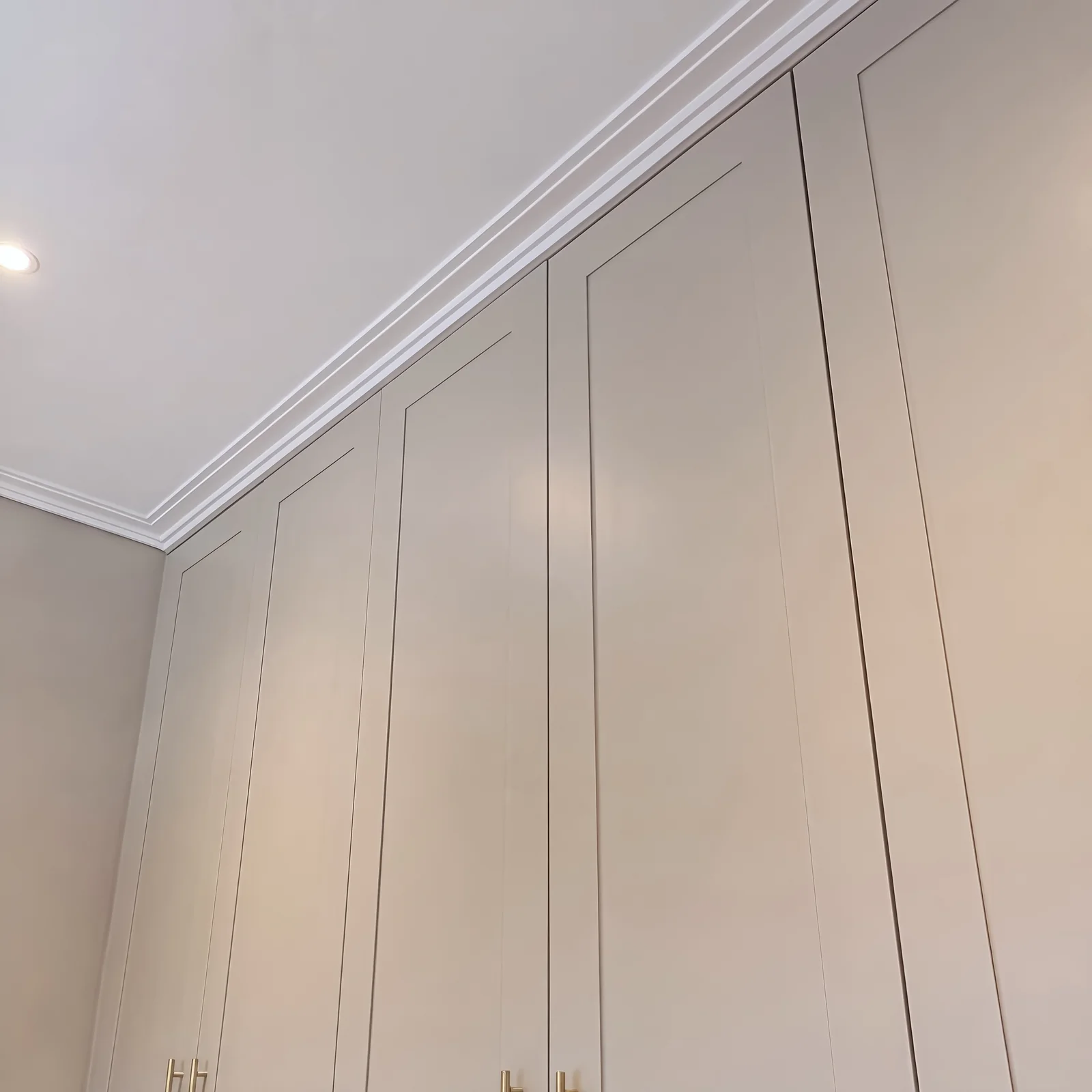 Close-up of pale grey wardrobe doors meeting a white cornice